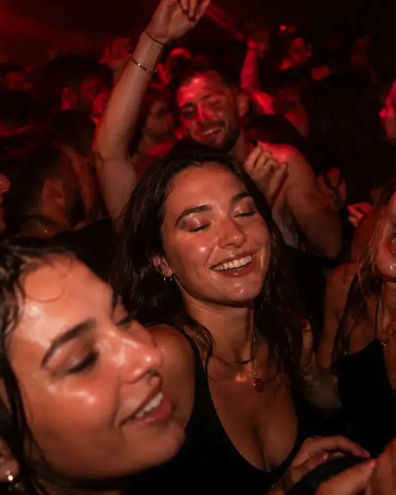 Friends dancing close together in a warmly lit club crowd.